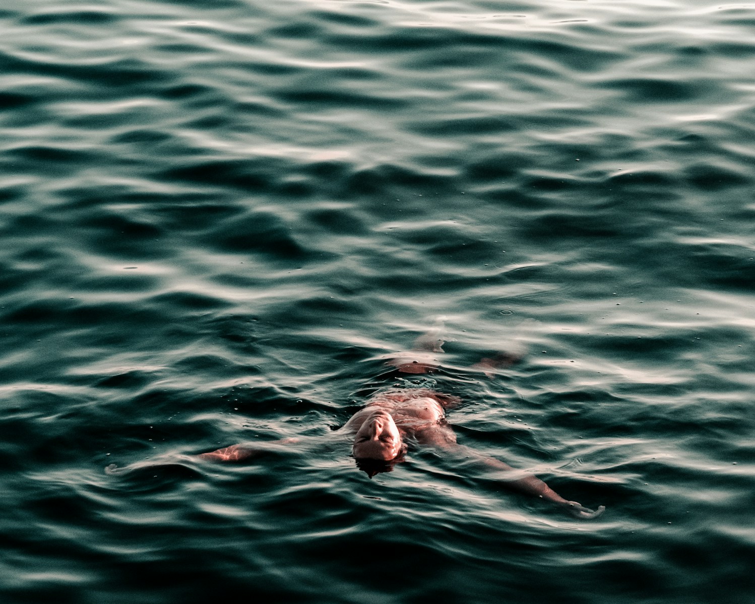 man swimming backwards on body of water