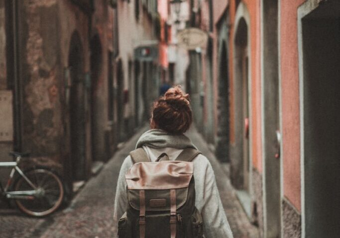 woman walking on street surrounded by buildings