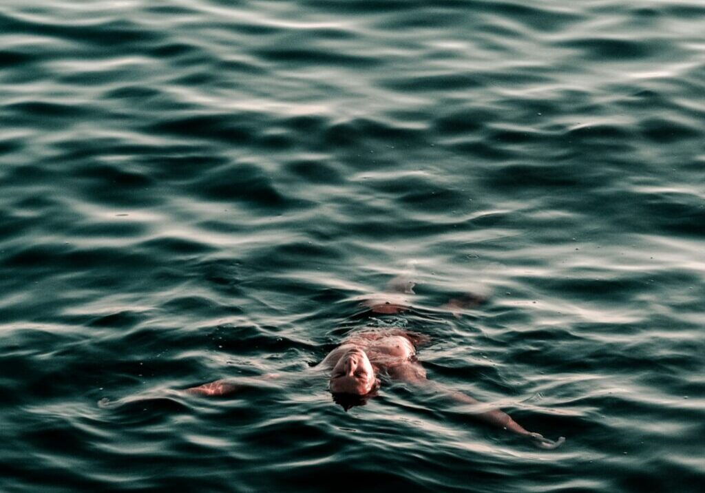 man swimming backwards on body of water